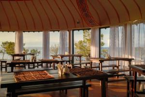 a dining room with tables and large windows at Ak-Sai Travel Oimo-Tash Yurt Camp in Kaji-Say