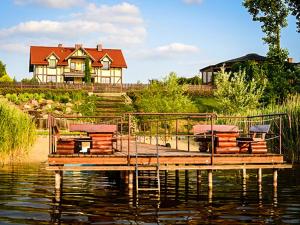 a house sitting on top of a lake with a dock at Agroturystyka Bobrowa Chata in Iława