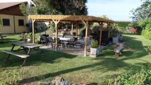 a picnic table and chairs under a pavilion in a yard at Villa Maëlla- Gîtes en Normandie, tout confort, SPA et Piscine in Saint-Michel-la-Forêt