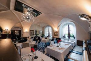 a restaurant with white tables and chairs and a chandelier at Hotel Grand in Český Krumlov