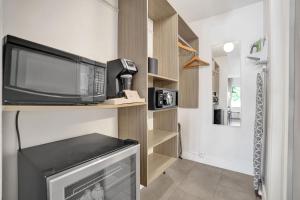 a kitchen with a microwave and a television on a shelf at King Suite at Ocean Blvd in Fort Lauderdale +29 photos