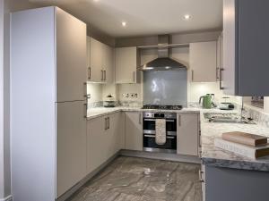 a kitchen with white cabinets and a stove top oven at Spring Gardens in Lower Darwen