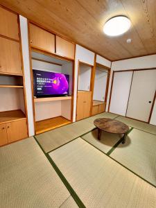 a living room with a table and a tv at Glad Kasuga in Kasugabaru