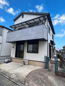 a white house with a black roof at Glad Kasuga in Kasugabaru