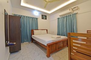 a bedroom with a bed in a room with blue curtains at Hotel De Lux Splendid in Pondicherry