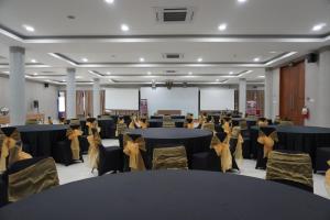 a banquet hall with black tables and chairs at Patra Parapat Hotel in Sibagading