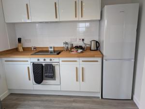 a kitchen with white cabinets and a white refrigerator at Rousay&nbspCottage in Orkney +5 photos