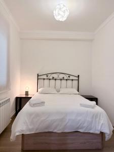 a white bedroom with a large bed with white sheets at Apartamento Oyón in Logroño