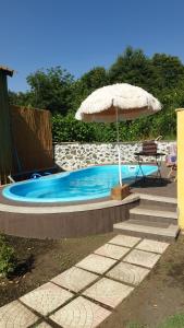 a umbrella and a chair next to a swimming pool at Soffio dell'Etna in Puntalazzo