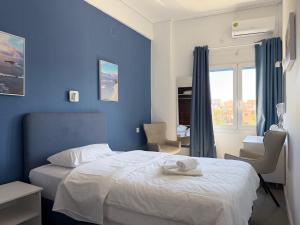 a blue bedroom with a bed and a window at Hotel Avra in Egina