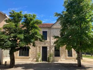 a stone house with two trees in front of it at La Maison du Parc in Saint-Vite
