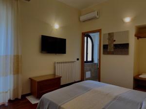 a bedroom with a bed and a television on the wall at Hotel Del Corso in SantʼAntìoco