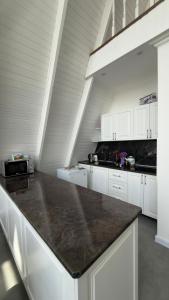 a kitchen with white cabinets and a black counter top at Gabala A frame Guest villa in Gabala