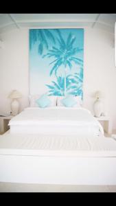 um quarto com uma cama branca e um mural de palmeira em Harmony Villas em Kuta