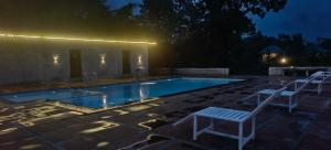 a swimming pool at night with two chairs around it at The Kiran's Resort Pench in Khawāsa