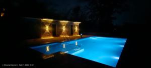 a swimming pool lit up at night with lights at The Kiran's Resort Pench in Khawāsa