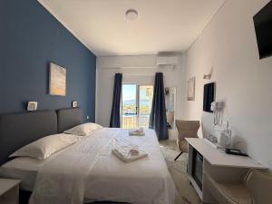 a bedroom with a bed and a desk and a window at Hotel Avra in Egina