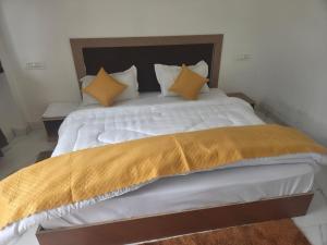 a large bed with white sheets and yellow pillows at Deep Heritage Hotel & Restaurant in Phata