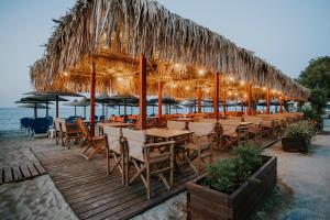 a restaurant with tables and umbrellas on the beach at Villa Yianna in Nea Mesangala