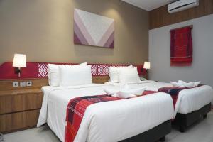 two beds in a hotel room with white sheets at Patra Parapat Hotel in Sibagading +52 photos