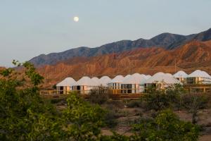 a row of white domes in front of a mountain at Ak-Sai Travel Oimo-Tash Yurt Camp in Kaji-Say
