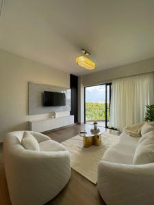 a living room with two white chairs and a television at Nyali Evoque - BriSta Stays in Mombasa +12 photos