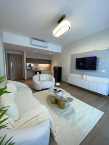 a living room with a white couch and a tv at Nyali Evoque - BriSta Stays in Mombasa
