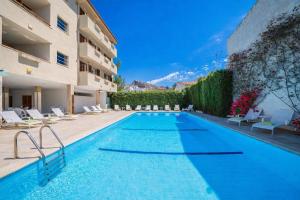 a swimming pool with chairs and a building at Apartamentos - Penthouse Bressol in Port de Pollensa