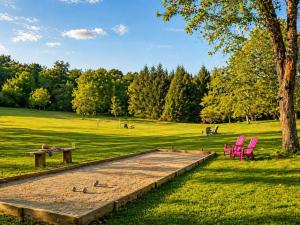 a park with pink chairs and a table and benches at La biche au bois piscine chauffee jacuzzi in Cazals