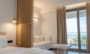 a bedroom with a couch and a large window at Pnoé Sea View Suites in Limenas