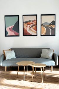 a living room with a couch and four framed paintings at Elbe Stay Roudnice in Roudnice nad Labem +2 photos