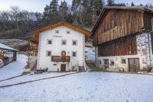 a large white house with a barn in the snow at Schoenau Bio & SPA Family Apartments in San Pietro in Laion