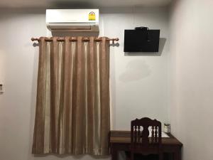 Habitación con calentador, cortina y mesa. en Jim Guesthouse, en Kanchanaburi