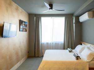 a bedroom with a bed with a ceiling fan and a window at Downtown photographer's studio 2 in Korinthos