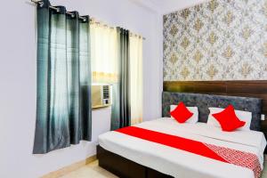 a bedroom with a large bed with red pillows at Hotel O Raama in Lucknow