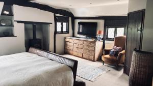 a bedroom with a bed and a chair and a sink at Cottage in the Hambleden Valley in Henley on Thames