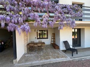 a building with a table and chairs and purple flowers at Logement indépendant avec jardin in Beaune