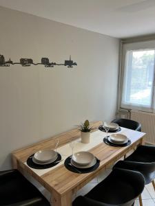 a wooden table with plates and wine glasses on it at Logement indépendant avec jardin in Beaune +4 photos