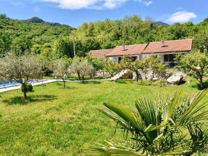 a house in a field with a yard with trees at Rustic Village House 4 in Rijeka Crnojevića
