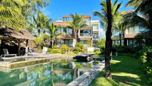 a resort with a swimming pool and palm trees at Beach Penthouse BELMARE in Belle Mare
