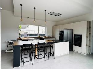 a kitchen with white cabinets and a large island with bar stools at Villa Wax - Piscine et plage in Santec