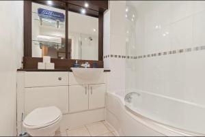 a bathroom with a toilet and a tub and a sink at Bright 2-BDR Apartment - Prime Central Location - Free Wi-Fi in Birmingham