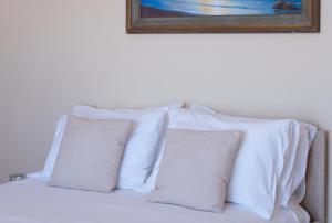 a pile of pillows on a bed with a picture above it at Sunset apartment by the sea in Palaiochórion