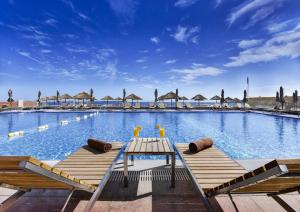 a large swimming pool with a table and benches at Braira Al Azizya Hotel & Resort in Al Khobar
