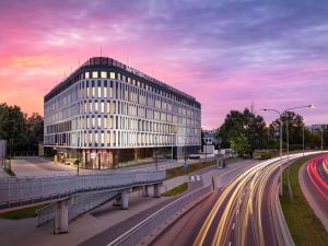 a building on a city street with cars in front of it at Mercure Warszawa Ursus Station in Warsaw