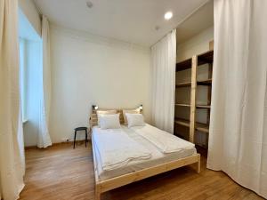 a bedroom with a bed with white walls and wooden floors at Zema11 Old Town Space in Vilnius