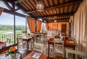 a restaurant with tables and chairs and a large window at Hotel La Fonte Del Cerro in Saturnia