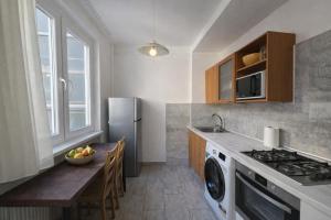 a kitchen with a table and a refrigerator at Comfort 65 2-Bedroom Apartment with Balcony in Miskolc