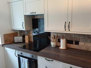 a kitchen with white cabinets and a wooden counter top at An Mor Haven in Coverack