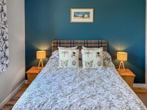 a bedroom with a bed with blue walls and two lamps at Kildonan in Laide